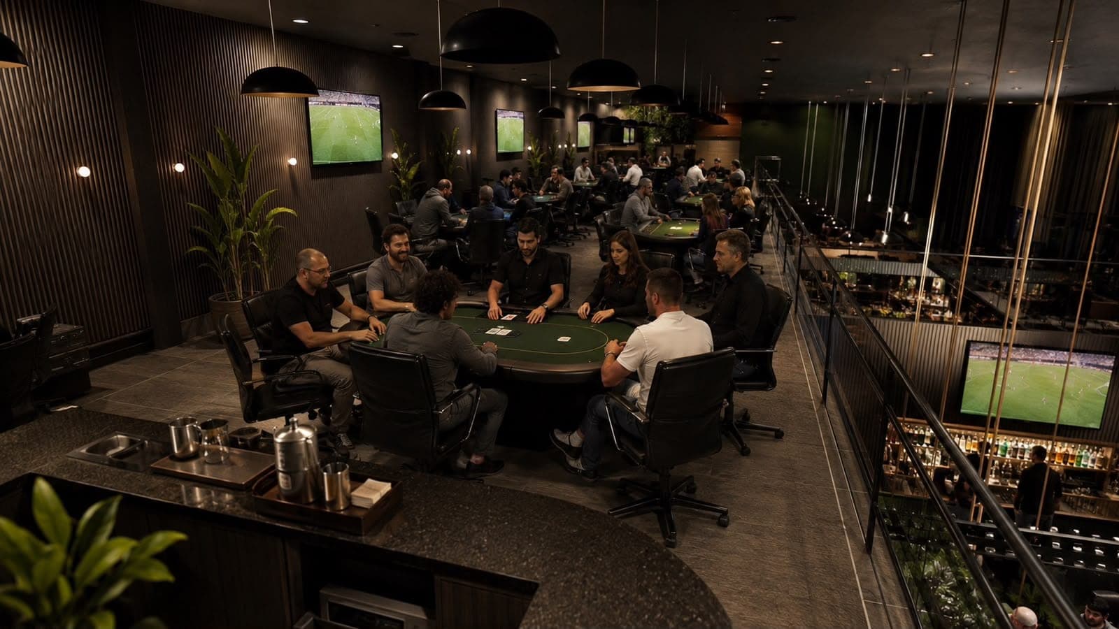 Vista do alto da sala de jogos, com várias mesas ocupadas e o bar no piso de baixo